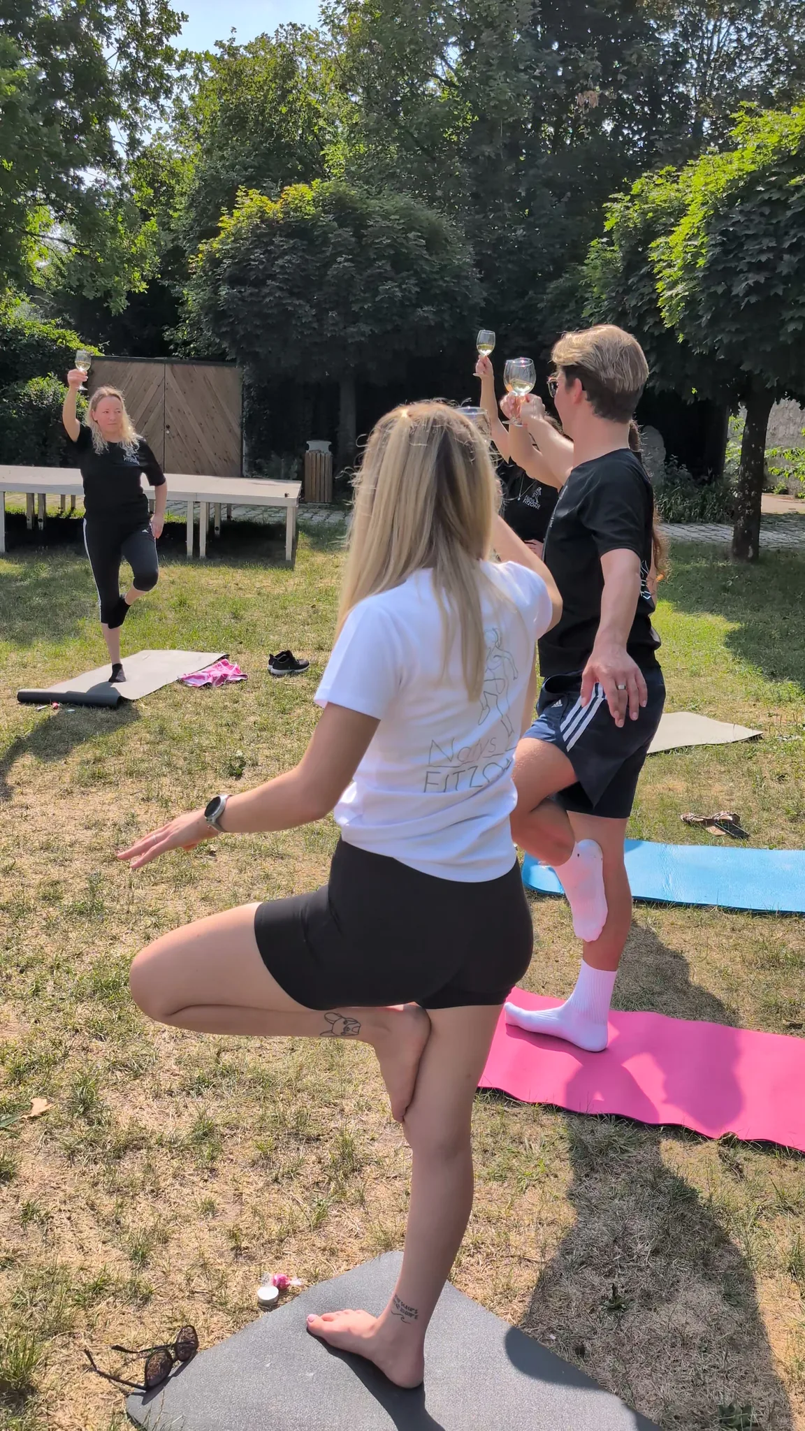 Wein-Yoga in Regensburg, Gruppe im Baum mit einem Glas Wein in der Hand